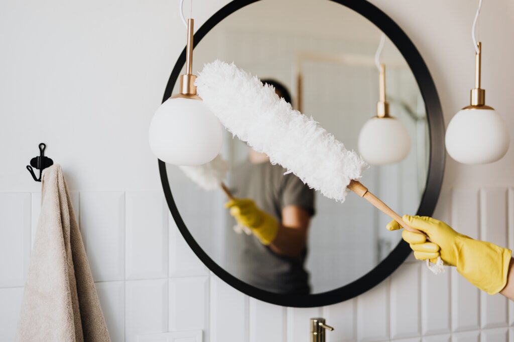 woman dusting lamp during cleaning service in central massachusetts